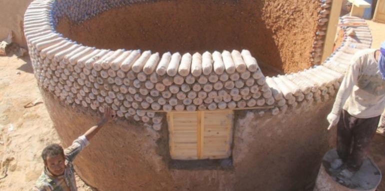 Refugiados construyen viviendas con botellas llenas de arena